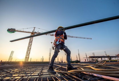 Bauarbeiter auf einem Dach trägt einen Stahlträger